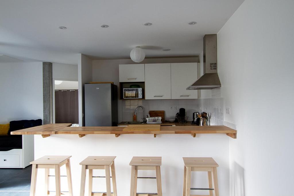 a kitchen with a counter and some stools in it at Appartement Neuf - Port de l'AberWrac'h - in Landéda