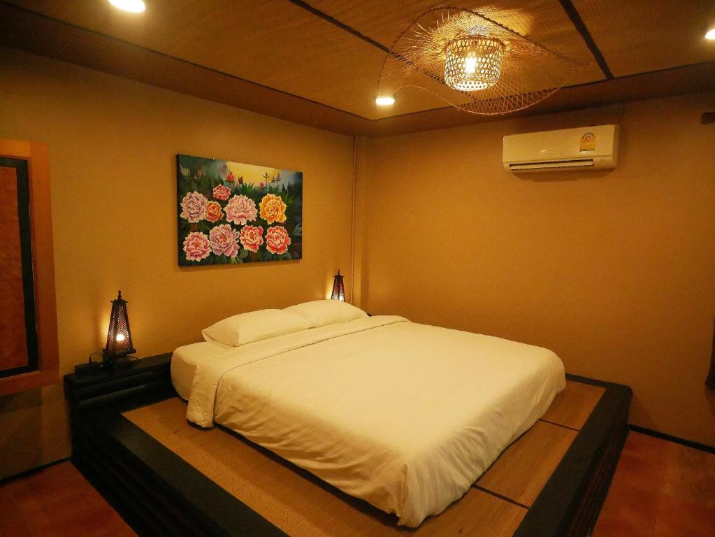 a bedroom with a white bed with a painting on the wall at Big Elk Steak House - HomeStay in Trat