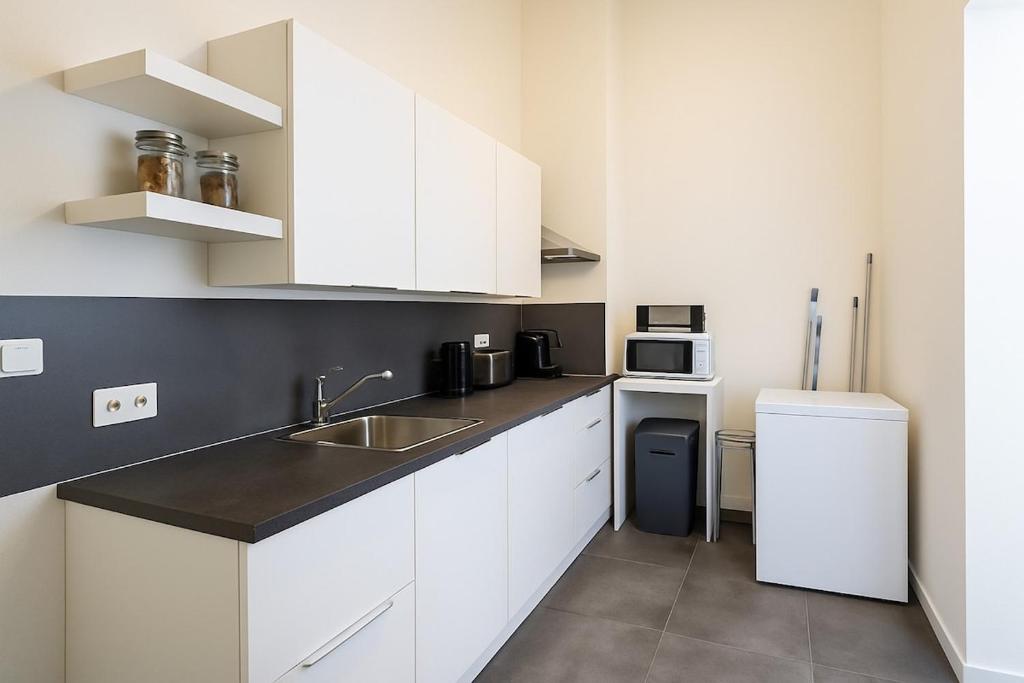 a kitchen with white cabinets and a sink and a refrigerator at Toison d'Or Apartment in Brussels