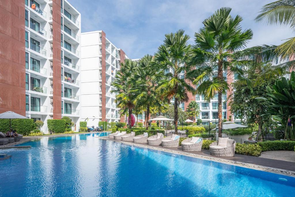 a swimming pool with palm trees and buildings at The One Chiang Mai 214 - Family Suite 2BR 2bath, Pool View near Central Festival in Chiang Mai