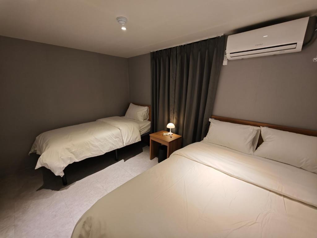 a hotel room with two beds and a lamp on a table at Unit D Hostel in Seoul