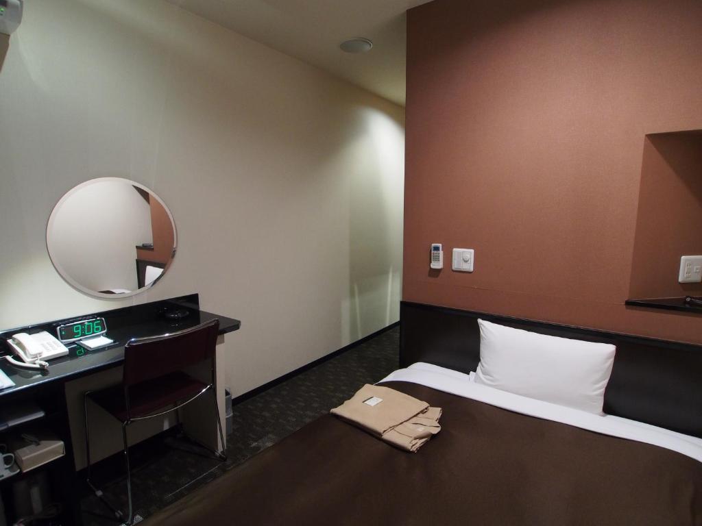 a hotel room with a bed and a mirror at Urbain Hiroshima Executive in Hiroshima