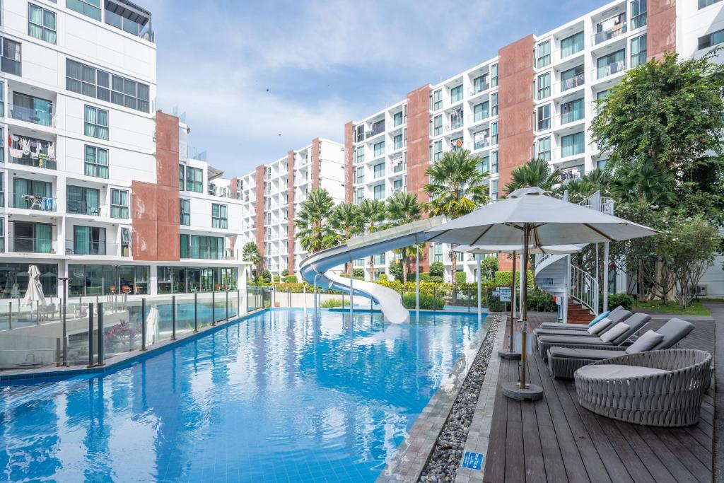 a swimming pool with chairs and an umbrella and some buildings at The One Chiang Mai 420 - Deluxe 1BDR Pool View near Central Festival in Chiang Mai