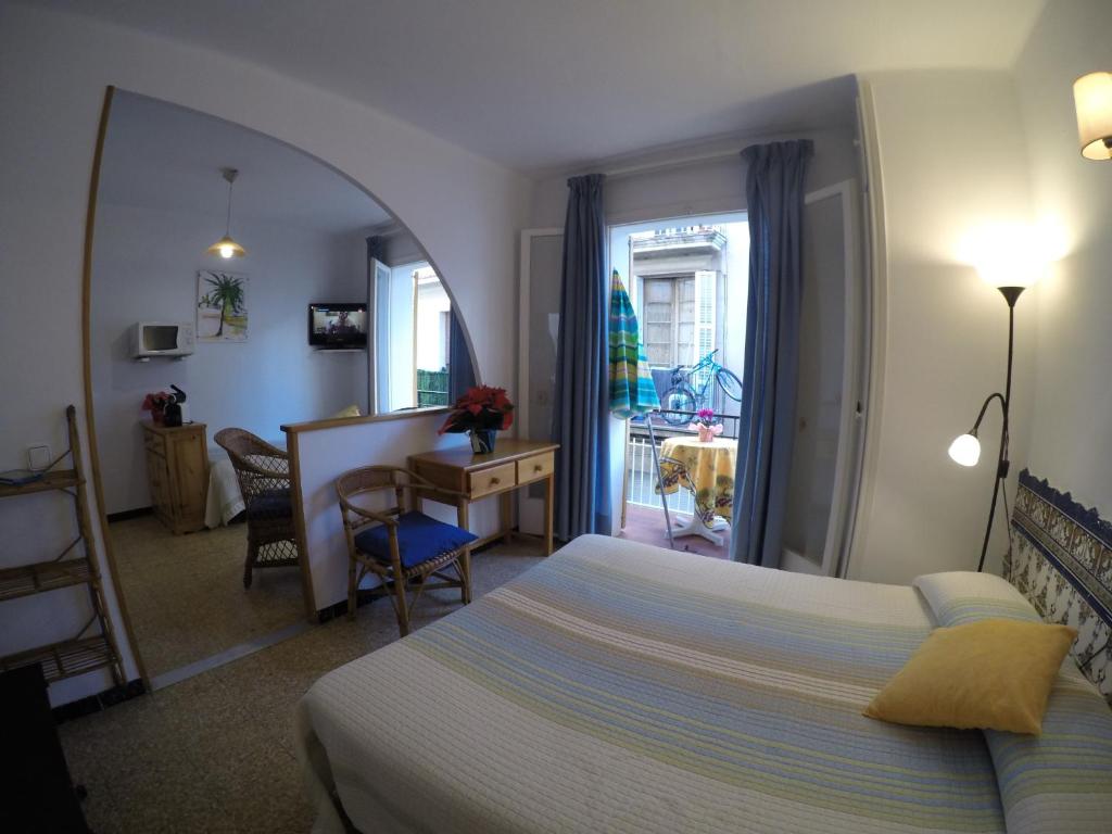 a bedroom with a bed and a desk and a room at Apartamentos Montserrat in Sitges