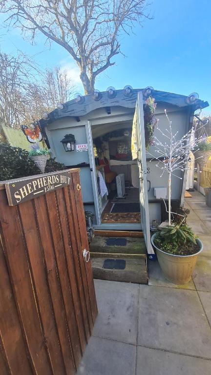 een klein huis met een open deur en een veranda bij Blue bells Small but quirky & Cozy Shepherd's Hut in Halkyn