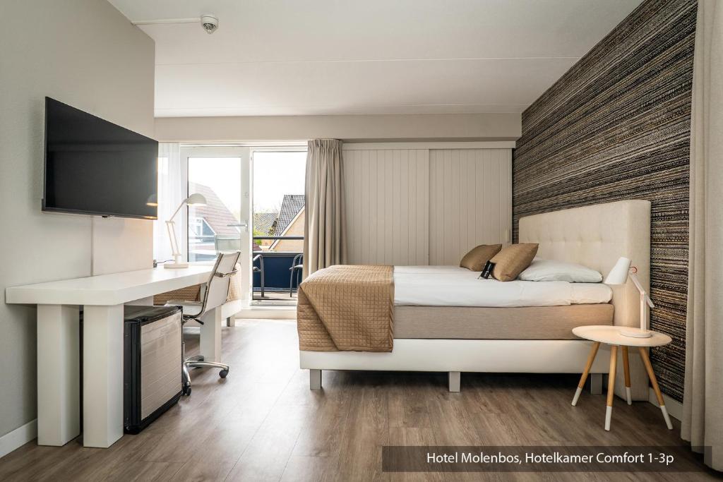 a bedroom with a bed and a desk and a computer at Hotel Molenbos Texel in De Cocksdorp