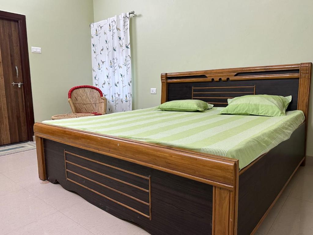 una cama grande con estructura de madera y sábanas verdes en Veridian Villa, en Kānpur