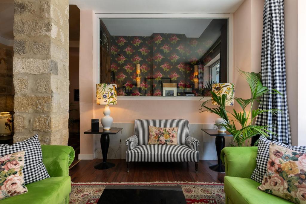 een woonkamer met 2 groene banken en een spiegel bij Hotel Carmen Boutique in Baeza