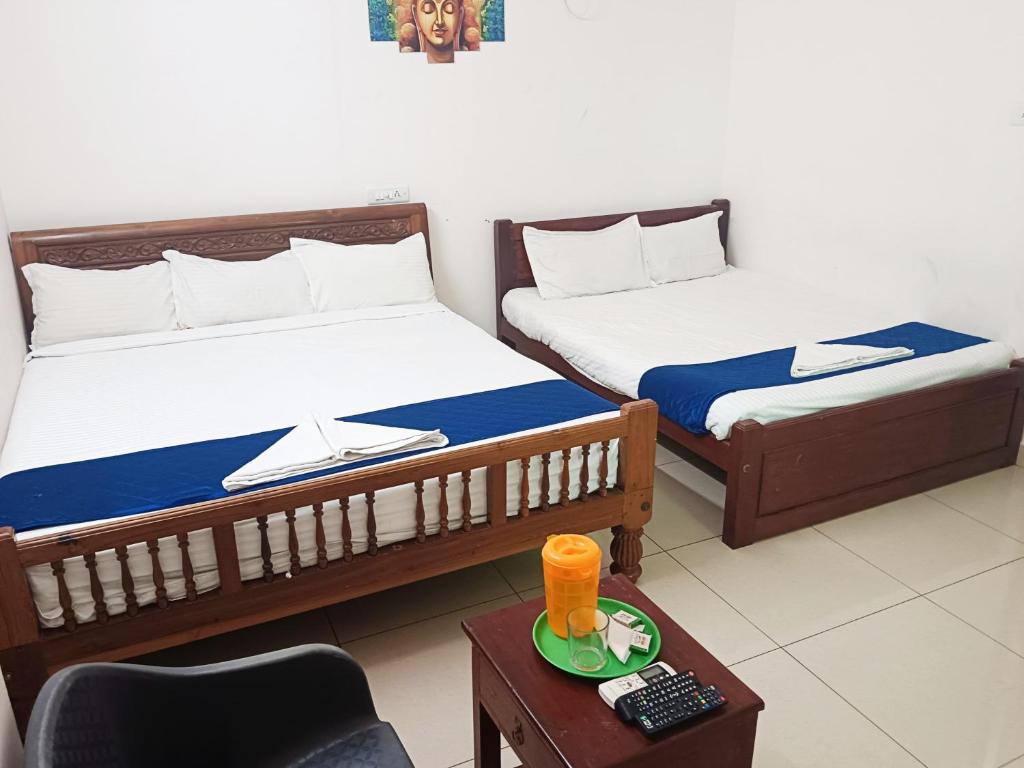 two beds in a room with a chair and a table at Dreamy beach in Puducherry