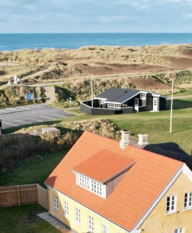 ein Haus mit orangefarbenem Dach direkt am Meer in der Unterkunft Strandhuset in Agger