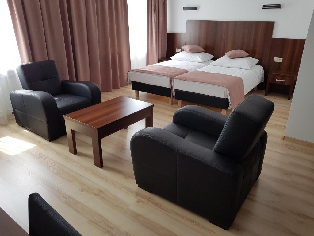 pokój hotelowy z 2 łóżkami, kanapą i krzesłami w obiekcie Pod Kominem Pokoje i Apartamenty w mieście Brzezie