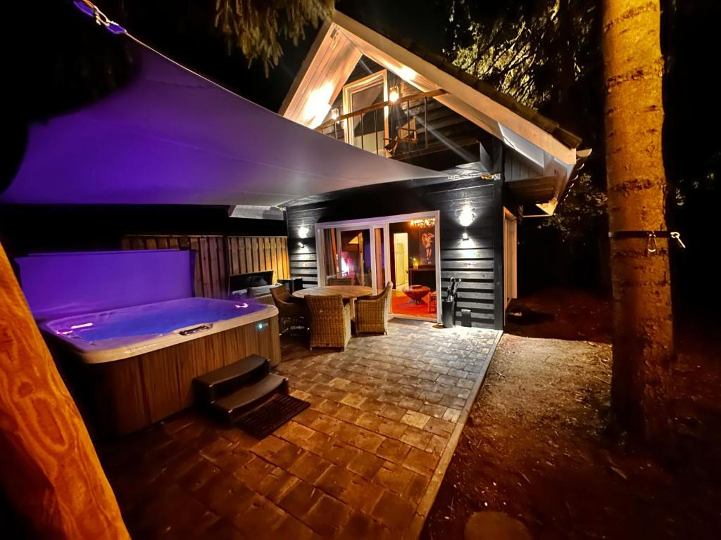 ein Haus mit einer Badewanne in der Mitte einer Terrasse in der Unterkunft Wellness Tuin - Ultieme Partner Beleving - Privé Wellness Vakantiehuis met Privé Jacuzzi in Privé tuin, Privé Indoor Sauna en Privé Indoor Stoomcabine in Koloniale Stijl - Gratis Fles Prosecco & Leuke Partner Connect Box ! in Horst