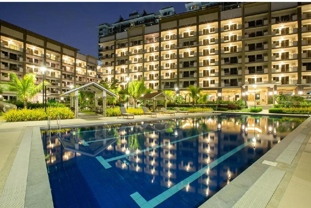 a hotel with a swimming pool in front of a building at Staycacia Haven 2BR Condo Maple Acacia Taguig in Manila
