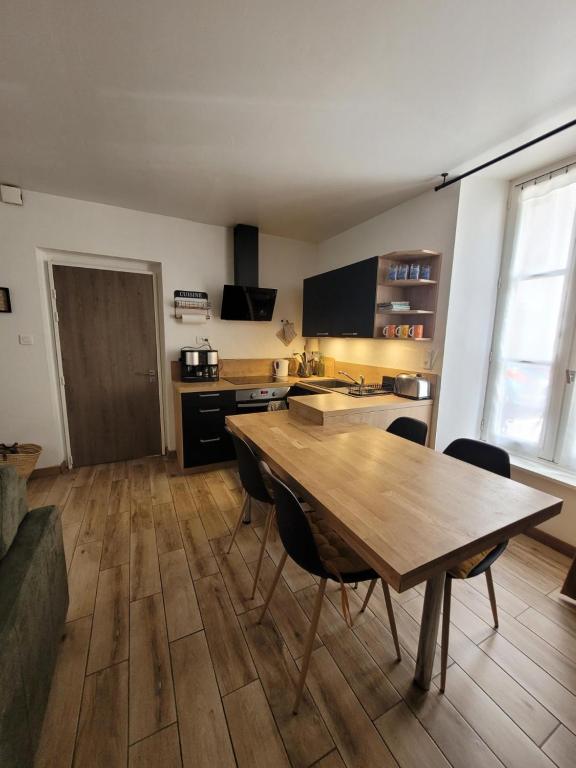 een keuken met een houten tafel en stoelen in een kamer bij DESQ29àCONCARNEAU in Concarneau