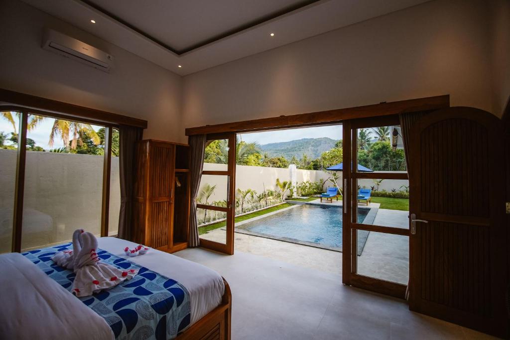 a child sitting on a bed in a bedroom with a pool at Bukti Garden Villas in Bukti