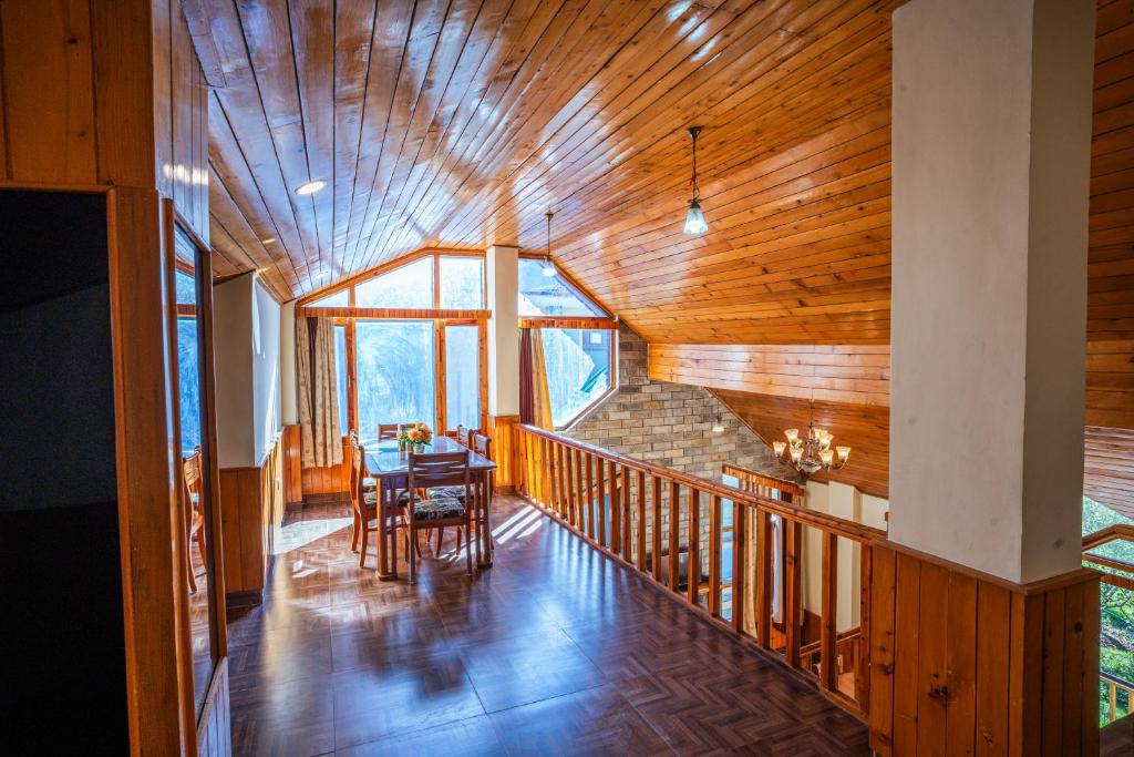 a room with a wooden ceiling and a dining room at The Northwood Cottages Manali, Mountain View with balcony, near mall road, manali in Manāli