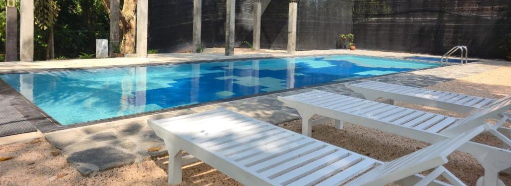 a swimming pool with a white bench and a whitevisorvisor at Ceylon Kingsmen Garden - Katunayake Airport Transit Hotels in Negombo