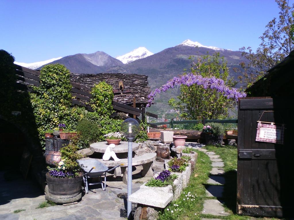 un jardín con mesa, sillas y montañas en Casa Mimosa 1 en Gressan