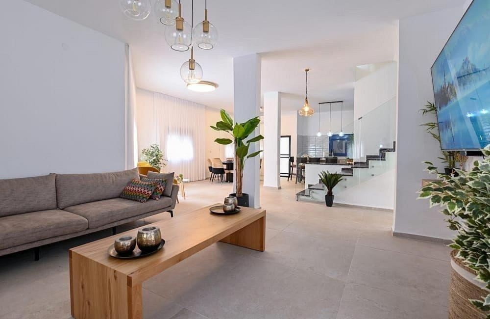 a living room with a couch and a table at אחוזת סנטוריני - וילה מהממת עם בריכה מחוממת וג'קוזי בעין יעקב in ‘Ein Ya‘aqov