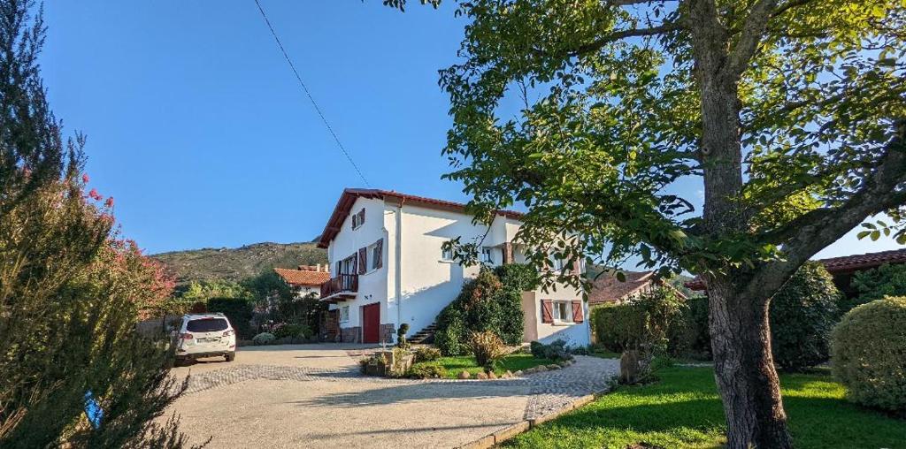 ein weißes Haus mit einem Auto, das in einer Einfahrt parkt in der Unterkunft Lau Haizeak Meublé 3 étoiles Ascain in Ascain