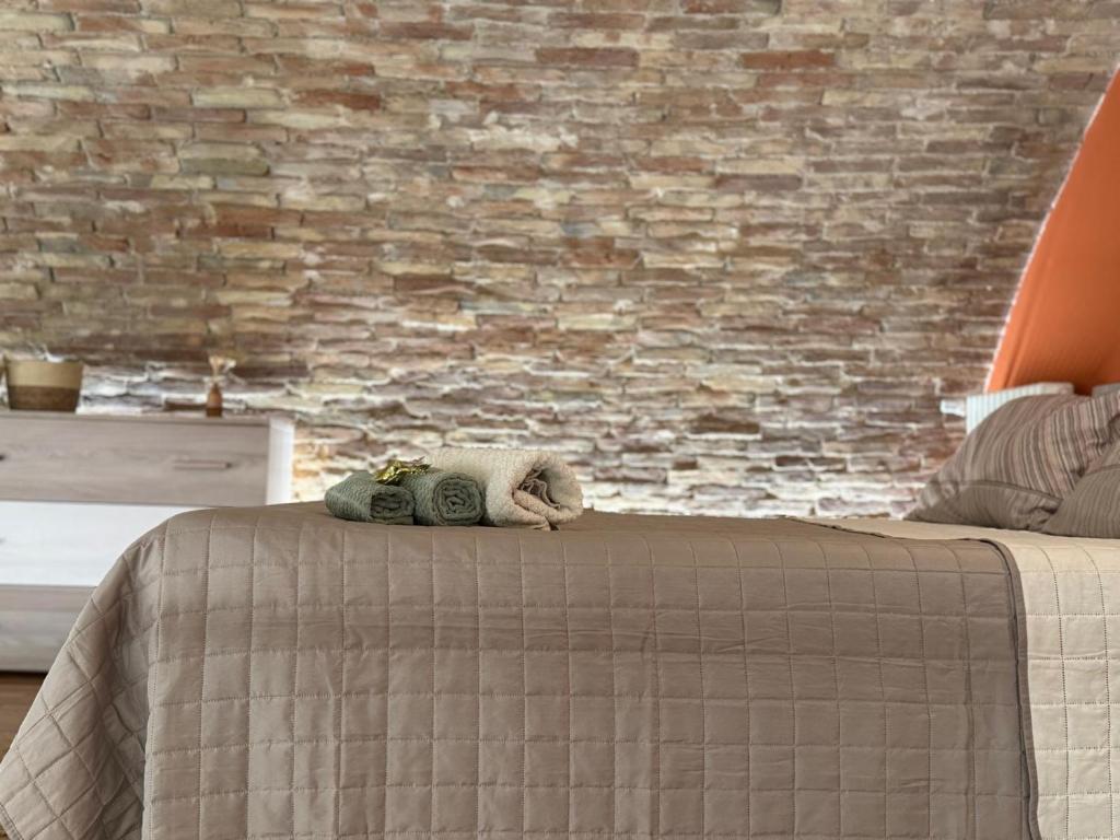 a bed in a bedroom with a brick wall at Dimora Sant'Anna Family Suite in Bernalda