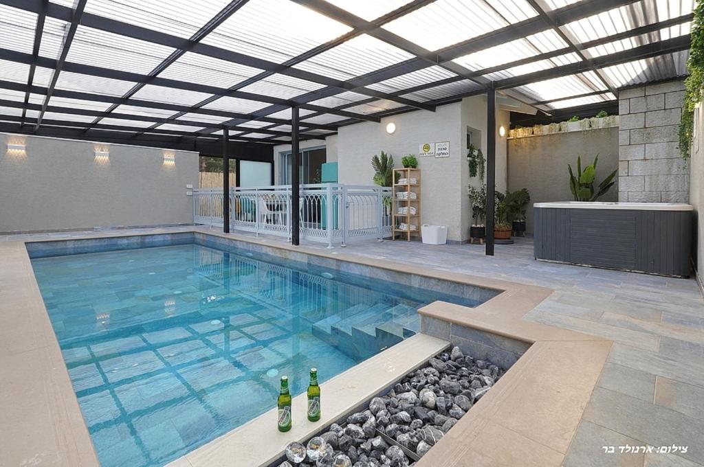 a swimming pool with wine bottles in the water at הילת השחר - וילה מדהימה עם 3 חדרי שינה ובריכה פרטית בעין יעקב in Mashabbe Sade