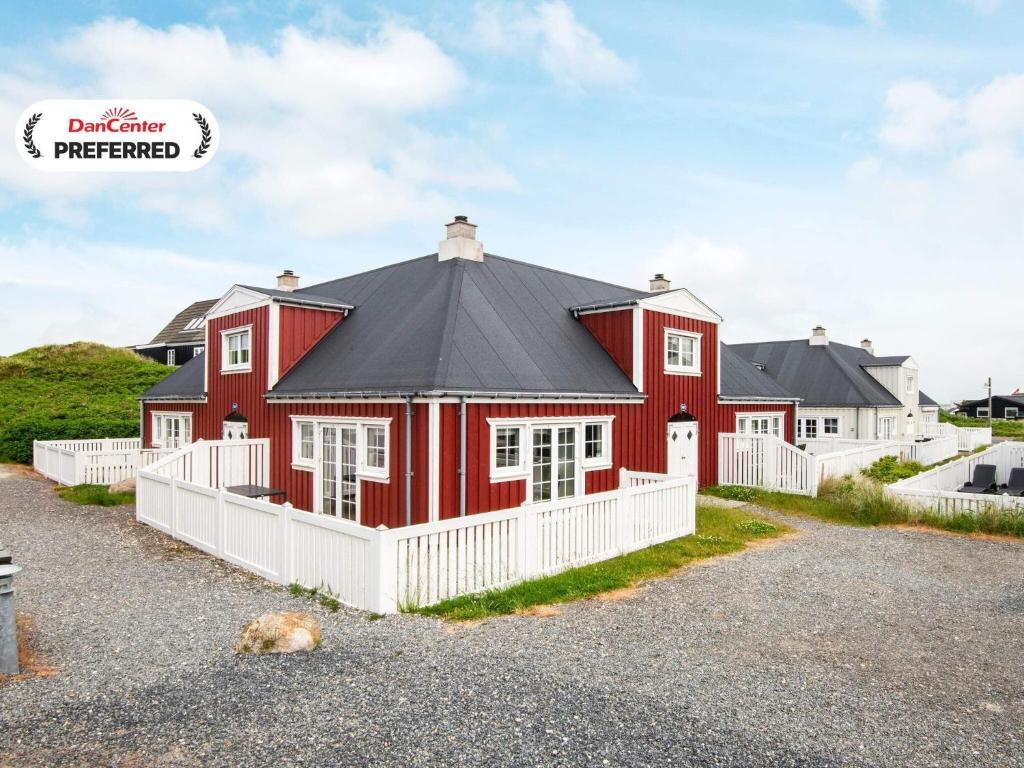 a red house with a black roof and a white fence at 4 person holiday home in Ringkøbing-By Traum in Ringkøbing