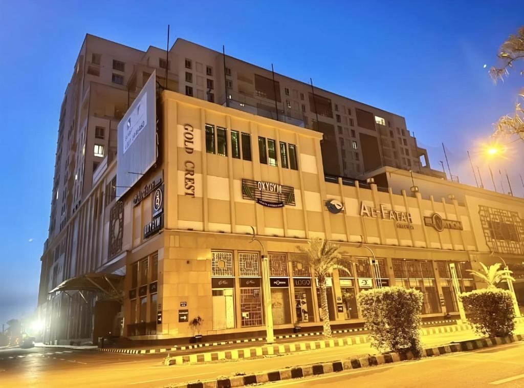 a large building in front of a street at night at Gold Crest Premium Hotel Serviced Apartments DHA Phase 4 Lahore in Lahore