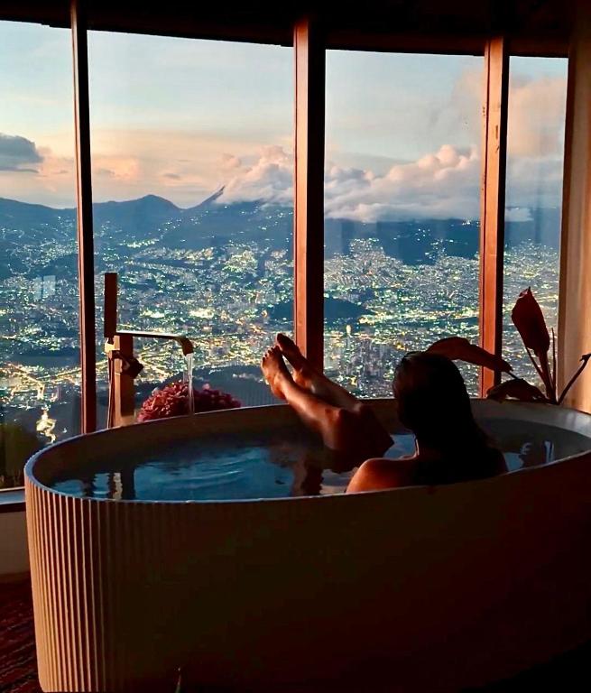 a woman in a bath tub with a view of a city at Cabaña en Santa Elena con vista a Medellín in Santa Elena