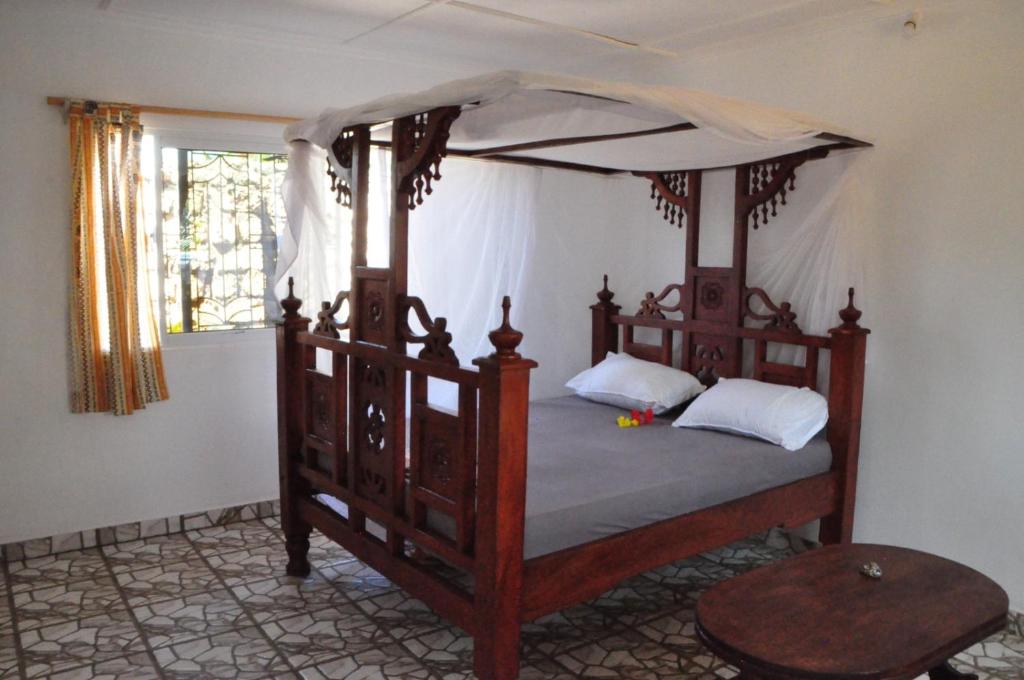 a bedroom with a wooden bed with a canopy at Bulu Apartments in Kilifi