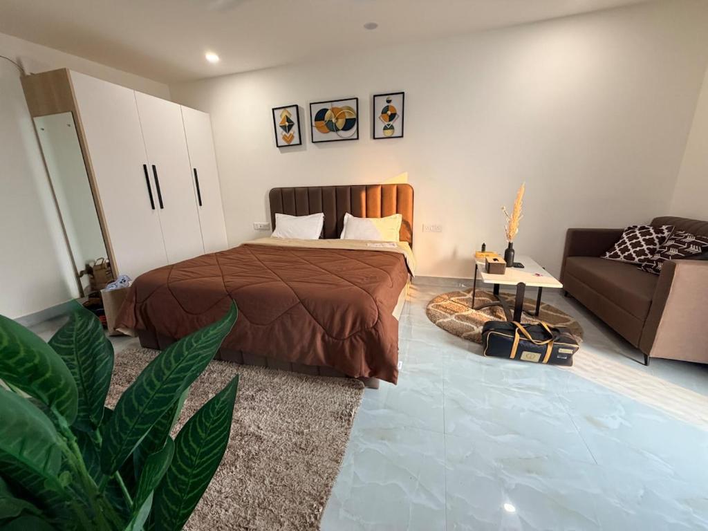 ein Schlafzimmer mit einem Bett und einer Couch in der Unterkunft Cozy Studio with Private Terrace & Golf Course View Road in Gurgaon