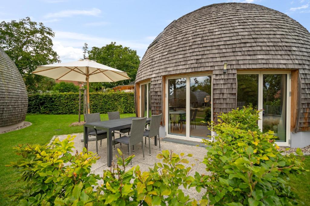 a circular house with a table and chairs and an umbrella at Nordkugel - Rundes Wohnglück am Tollensesee in Wustrow