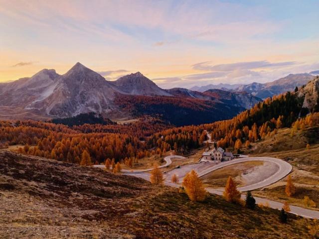 een kronkelende weg op een heuvel met bergen op de achtergrond bij Les granges d'Arvieux vue sur le Queyras in Arvieux