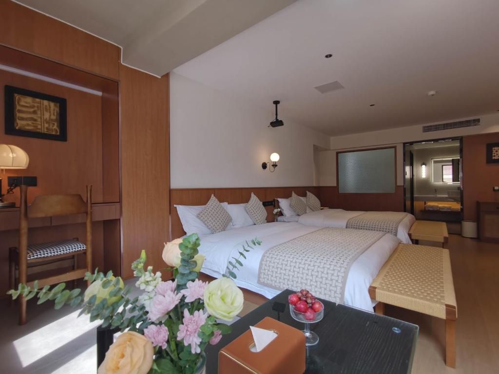 a bedroom with a large bed and a table with flowers at Tuji Lane and Fanghe Homestay (West Street Kaiyuan Temple Branch) in Quanzhou