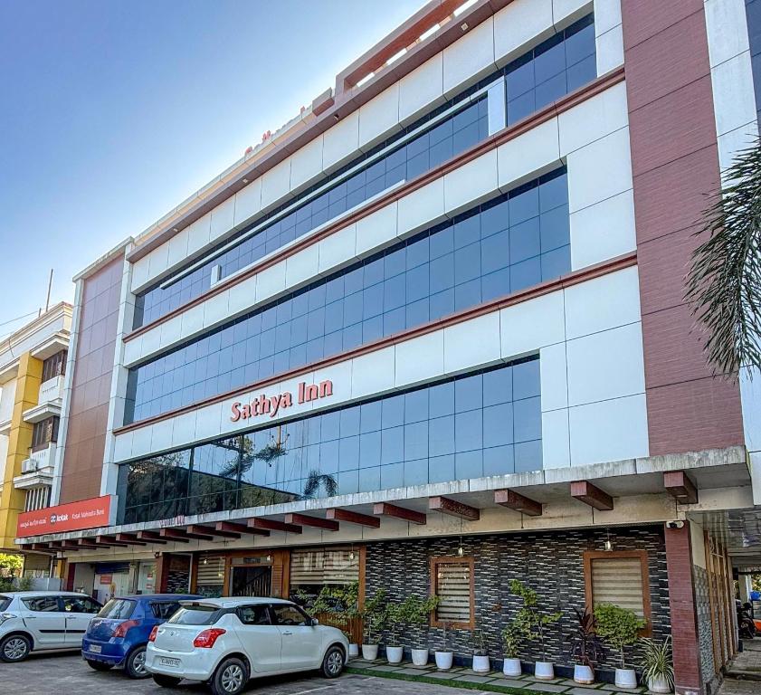 Un edificio con coches aparcados delante. en Sathya Inn Guruvayur, en Trichūr