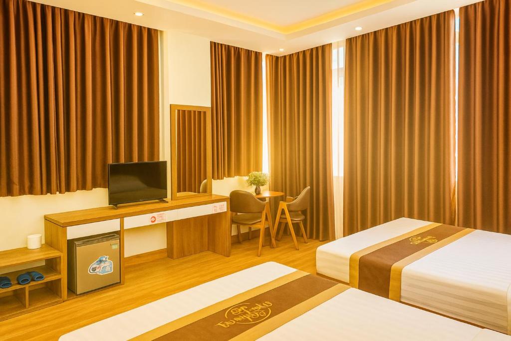 a hotel room with two beds and a television at Ngọc Tùng Hotel in Ha Long