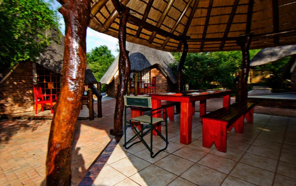 a patio with a table and chairs under an umbrella at Big Tuskers Bush Camp in Marloth Park