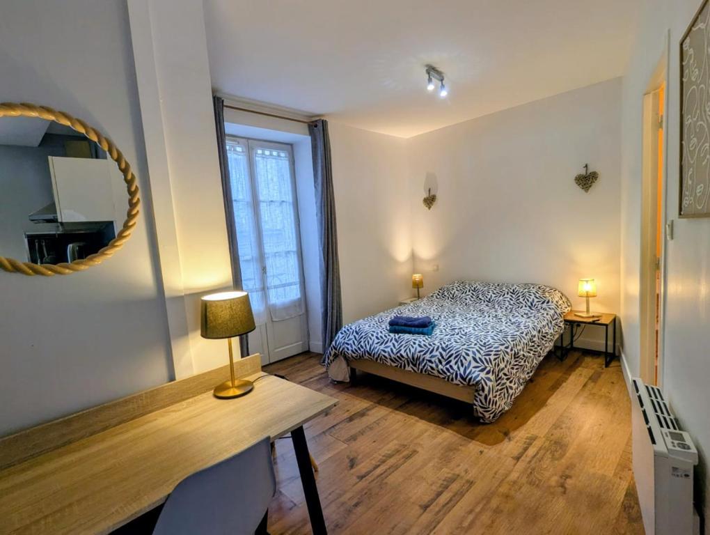 a bedroom with a bed and a table and a mirror at Charmant studio rénové hyper centre in Périgueux