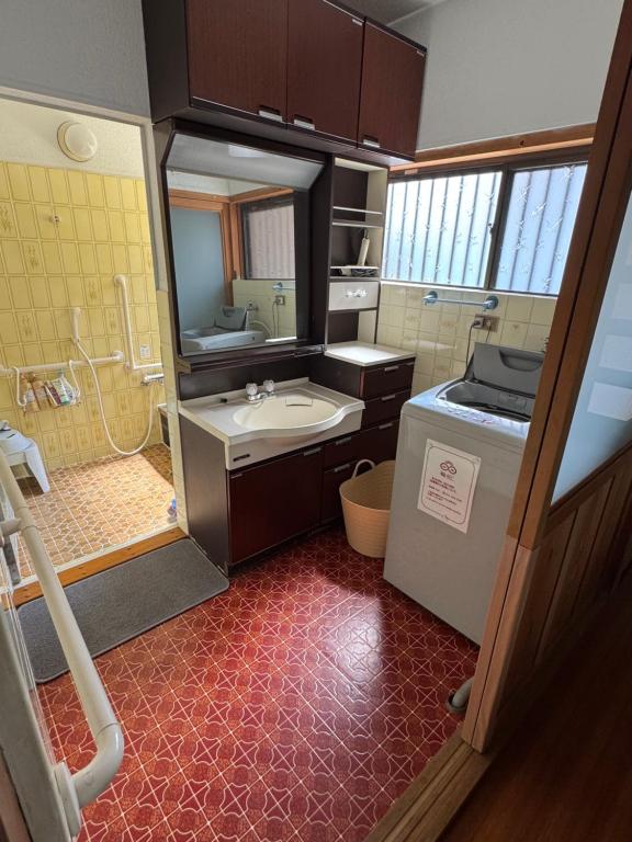 橋本市にあるゲストハウス輪の洗面台と洗濯機を備えた小さなバスルーム