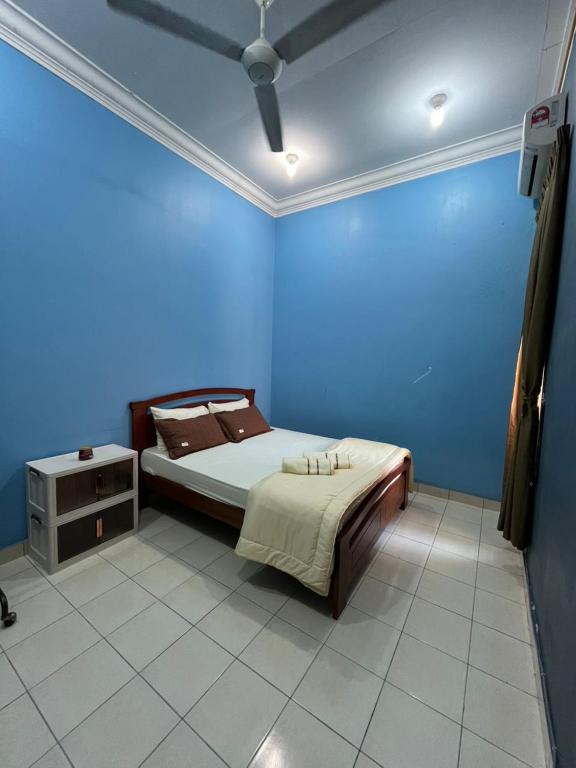 a bedroom with a bed and a blue wall at Kota Puteri Vibe Kampung Homestay in Batu Arang