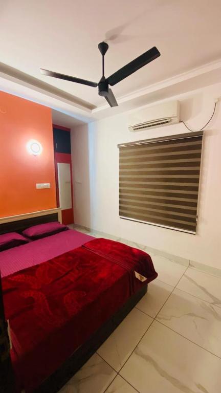a bedroom with a red bed and a ceiling fan at Rainbow apartments in Cochin