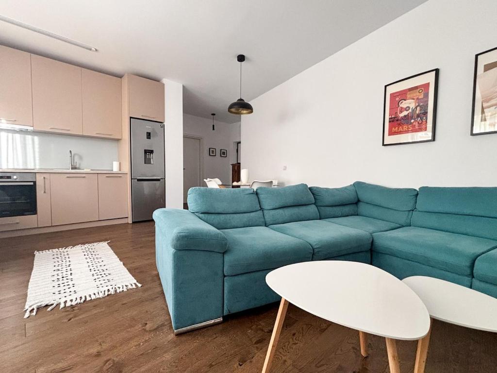 a living room with a blue couch and a kitchen at Sunshine Luxury Apartment Private Parking in Cluj-Napoca