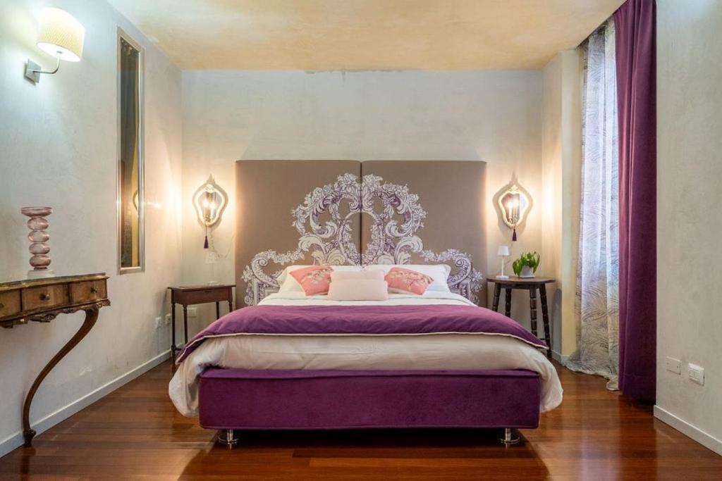 维罗纳SWEETHOME DOMUS 250mq nel centro di Verona con vista sul Teatro Romano的一间卧室配有一张特大号床和紫色床单