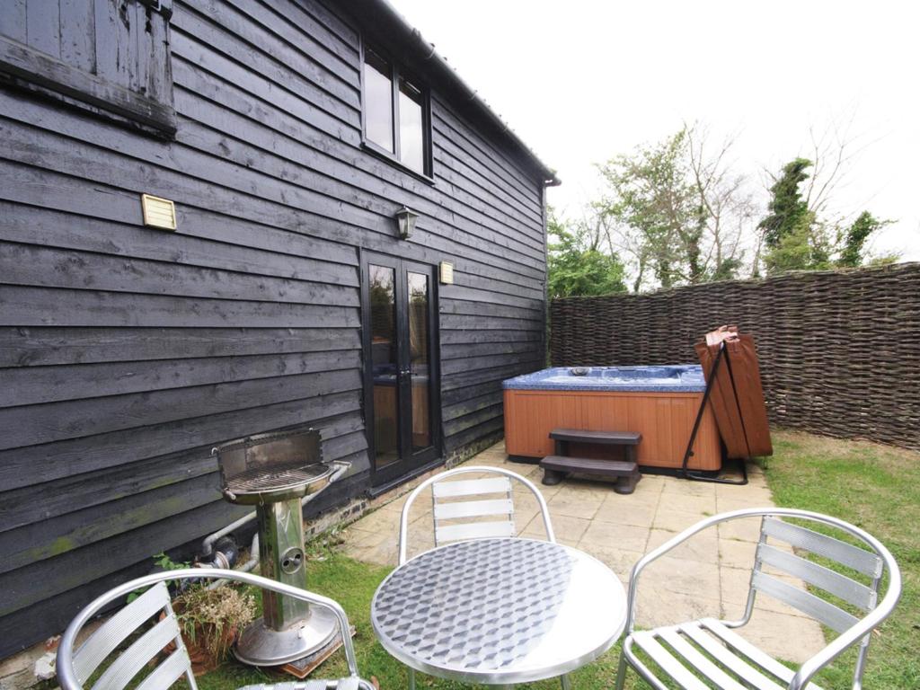 a patio with a table and chairs and a hot tub at The Cart Lodge-E3568 in Uggeshall