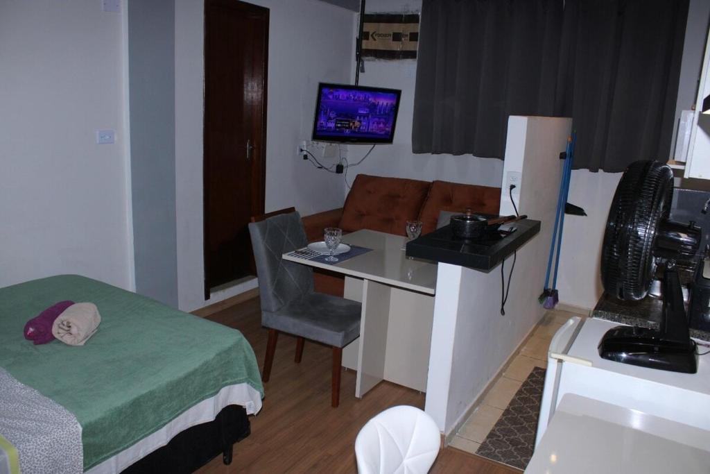 a room with a bed and a desk and a television at Studio11 near Drogasil in Ourinhos