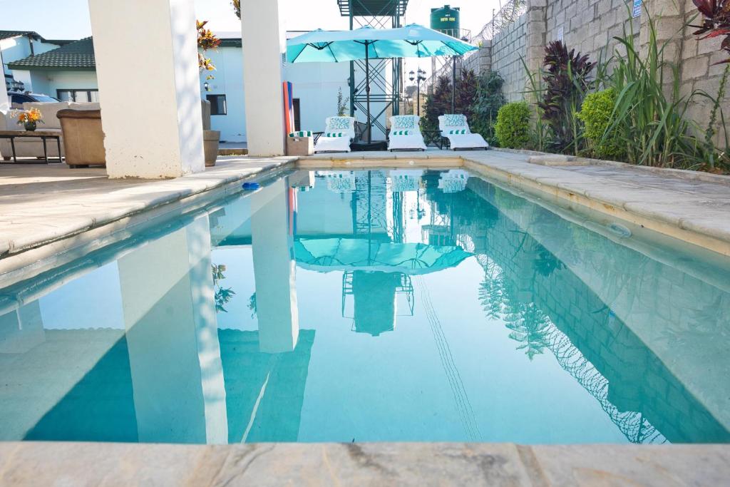 a swimming pool with two chairs and an umbrella at The Emerald Apartments Ibex Meanwood in Lusaka