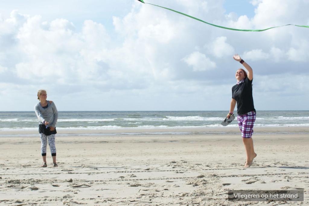 two people standing on the beach flying a kite at Camping Loodsmansduin in Den Hoorn