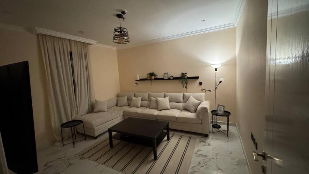 a living room with a white couch and a table at نسمة الخبر سويت in Dammam