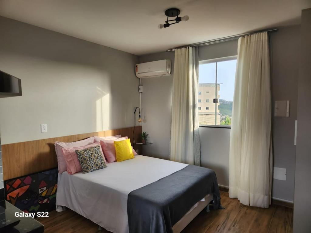 a bedroom with a bed with pillows and a window at Apê 301 a 2,8 km da UFV in Viçosa