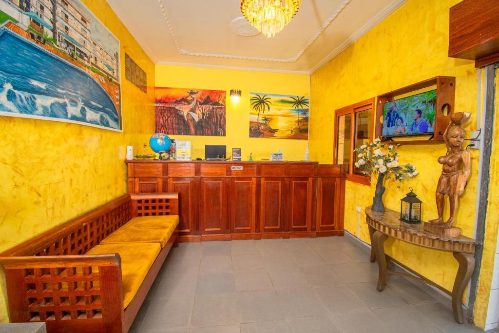 a yellow room with a bench and a table at Résidence Hôtelière TAZ in Kribi